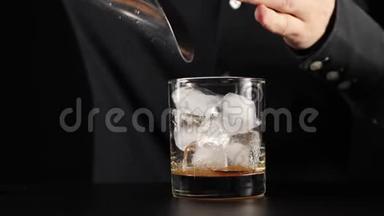 老式鸡尾酒。 酒保拿着勺子，从桶里拿了一些冰块，然后把冰块倒入一个加糖的杯子里